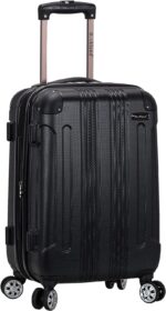 A black wheeled suitcase with a retractable handle stands upright. It features textured material and plastic corners for protection  suitable for travel in various environments like airports or train stations.