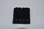 A black tactical pouch lies flat with three vertical straps and snaps on a white surface providing space for attachments or storage in a minimalist context.