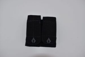 A dual pocket pouch made of black fabric features two secured compartments with flap closures placed on a plain white background  designed for carrying small items or tools.