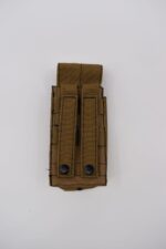 A brown tactical pouch rests flat on a white surface featuring two fastening straps and two black buttons positioned at the bottom demonstrating a compact design for equipment storage.