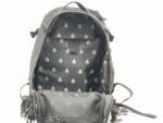 A black backpack lies open revealing its interior with a patterned lining and a mesh compartment at the bottom showcasing a spacious design suitable for storage or organization.