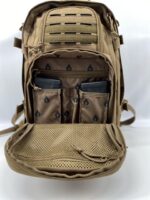 A tan tactical backpack is open displaying multiple compartments The main section contains two magazines housed in mesh pockets alongside a front mesh zippered compartment for additional storage