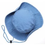 A blue bucket hat sits upright displaying its wide brim and rounded crown with a chin strap attached suggesting use for sun protection in outdoor activities.