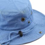 A blue bucket hat with a round crown features ventilation grommets and a drawstring for secure fit rests against a plain white background.