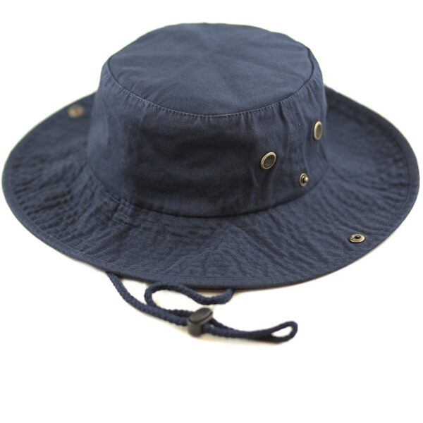 A navy blue bucket hat rests on a white surface featuring a round crown and a wide brim with ventilation holes and an adjustable chin strap for secure wear.