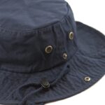 A navy blue bucket hat features a wide brim and metal eyelets for ventilation the hat rests against a plain white background emphasizing its texture and design details.