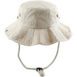 A beige bucket hat features a wide brim and ventilation holes. It is secured with a chin strap that has an adjustable toggle  suggesting suitability for outdoor activities.
