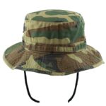 A camouflage bucket hat rests upright showcasing a wide brim and drawstring for secure wear perfect for outdoor activities or military use in a natural environment