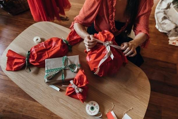 Woman wrapping a gift using 100% cotton bandanas with various creative wrapping styles for eco-friendly and stylish gift presentation.