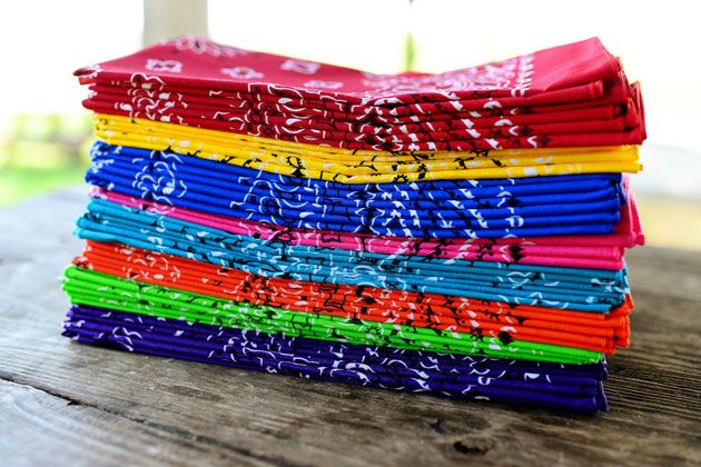 A neatly arranged stack of colorful bandannas resting on a wooden table, highlighting their diverse designs