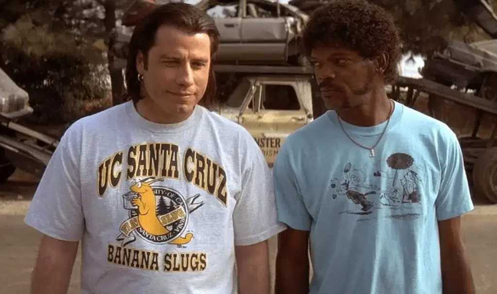 Celebrity Fashion: Tops, T-Shirts, Shirts, Hoodies, Jackets & More | Two men stand side by side outdoors, wearing casual graphic T-shirts. One shirt reads "UC Santa Cruz Banana Slugs." Their expressions are calm and serious.