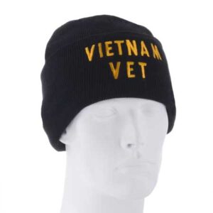 A black knit beanie displays the embroidered text "VIETNAM VET" in yellow letters resting on a plain white mannequin head set against a neutral background.
