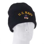 A black beanie hat displays "U.S. NAVY" in yellow lettering and features an embroidered emblem. It sits on a white mannequin head against a plain background.