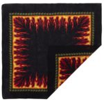 A patterned black cloth features a vibrant flame design in red and yellow along its borders with geometric accents creating a striking visual effect that evokes heat and intensity.
