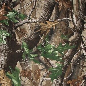 A pattern of intertwined brown branches and green leaves creates a natural camouflage effect against a background of trees and foliage suggesting a woodland environment.