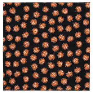A patterned fabric features multiple orange jack-o'-lanterns with various facial expressions set against a solid black background creating a festive Halloween theme throughout the material.