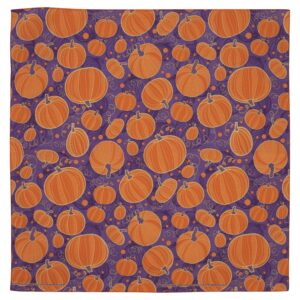 A patterned fabric features various sizes of orange pumpkins scattered across a purple background with spiral designs and small circles  creating a festive autumnal theme.