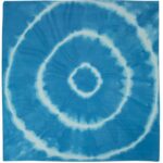 A blue fabric features a spiral tie-dye pattern with concentric circles in lighter blue and white creating a symmetrical design against a solid background.