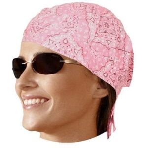 A woman wears a bright pink bandana and sunglasses while smiling. She appears to be in a relaxed or outdoor setting  suggesting a casual or sunny environment.