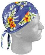 A blue floral-patterned headscarf is tied around a mannequin head with a smooth surface displaying vibrant yellow and orange flowers and green leaves against a tropical background.
